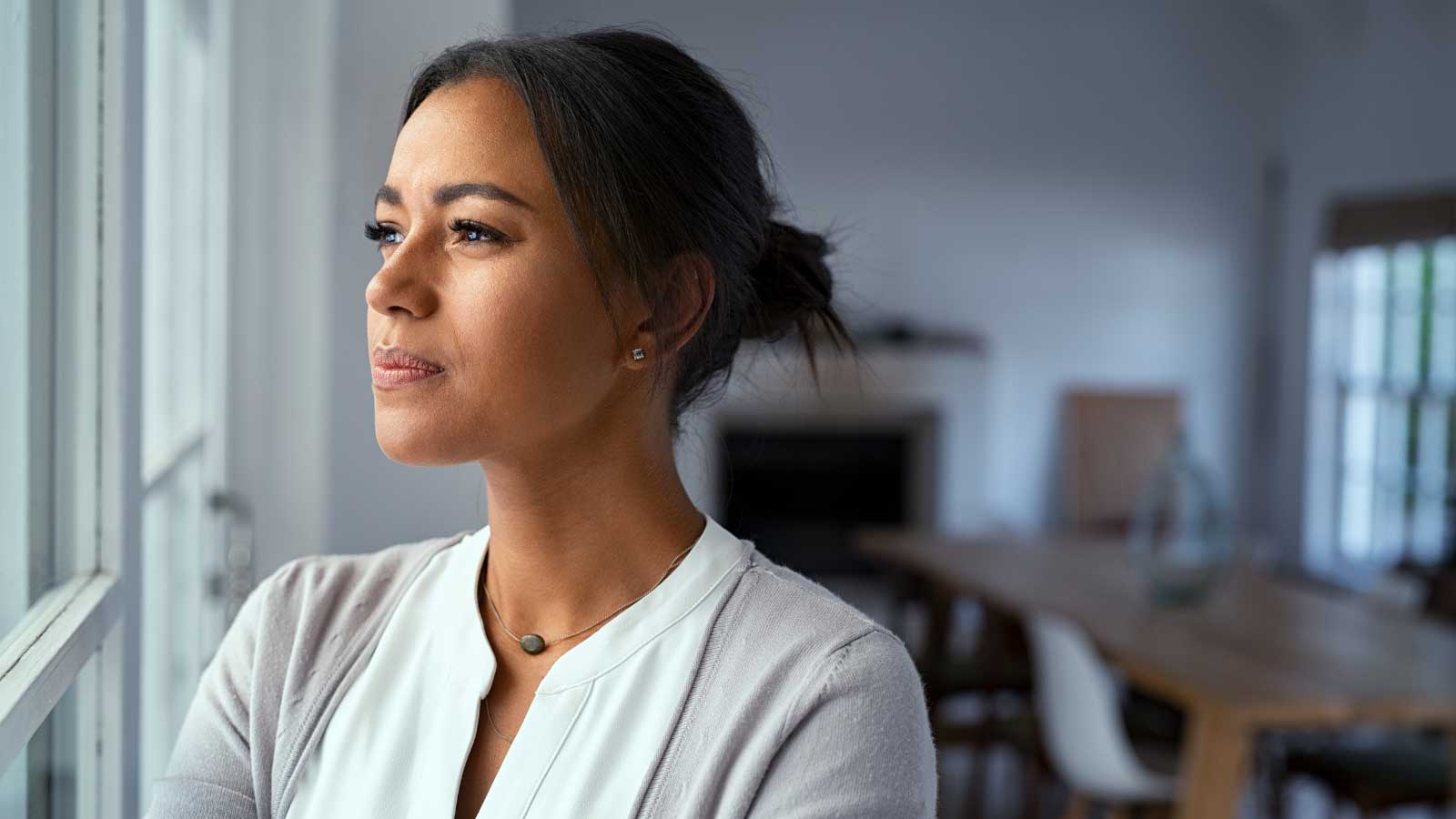 A thoughtful woman gazes out a window, reflecting quietly