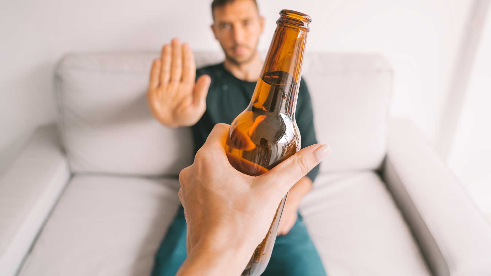 Man refusing a beer bottle with a hand gesture.