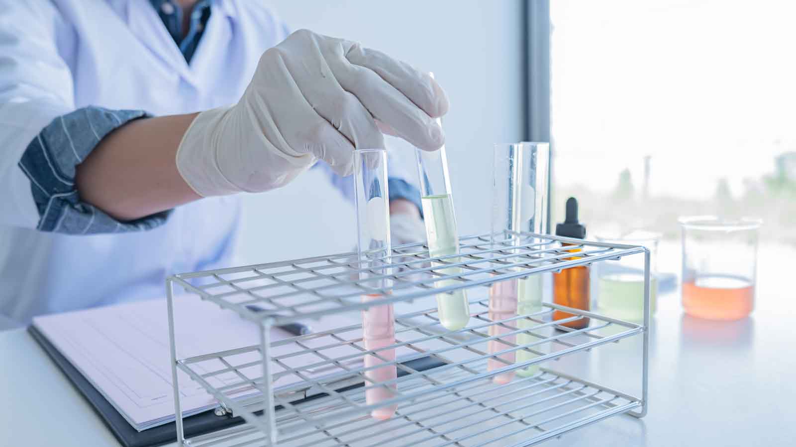 Scientist handling test tubes in a lab setting.