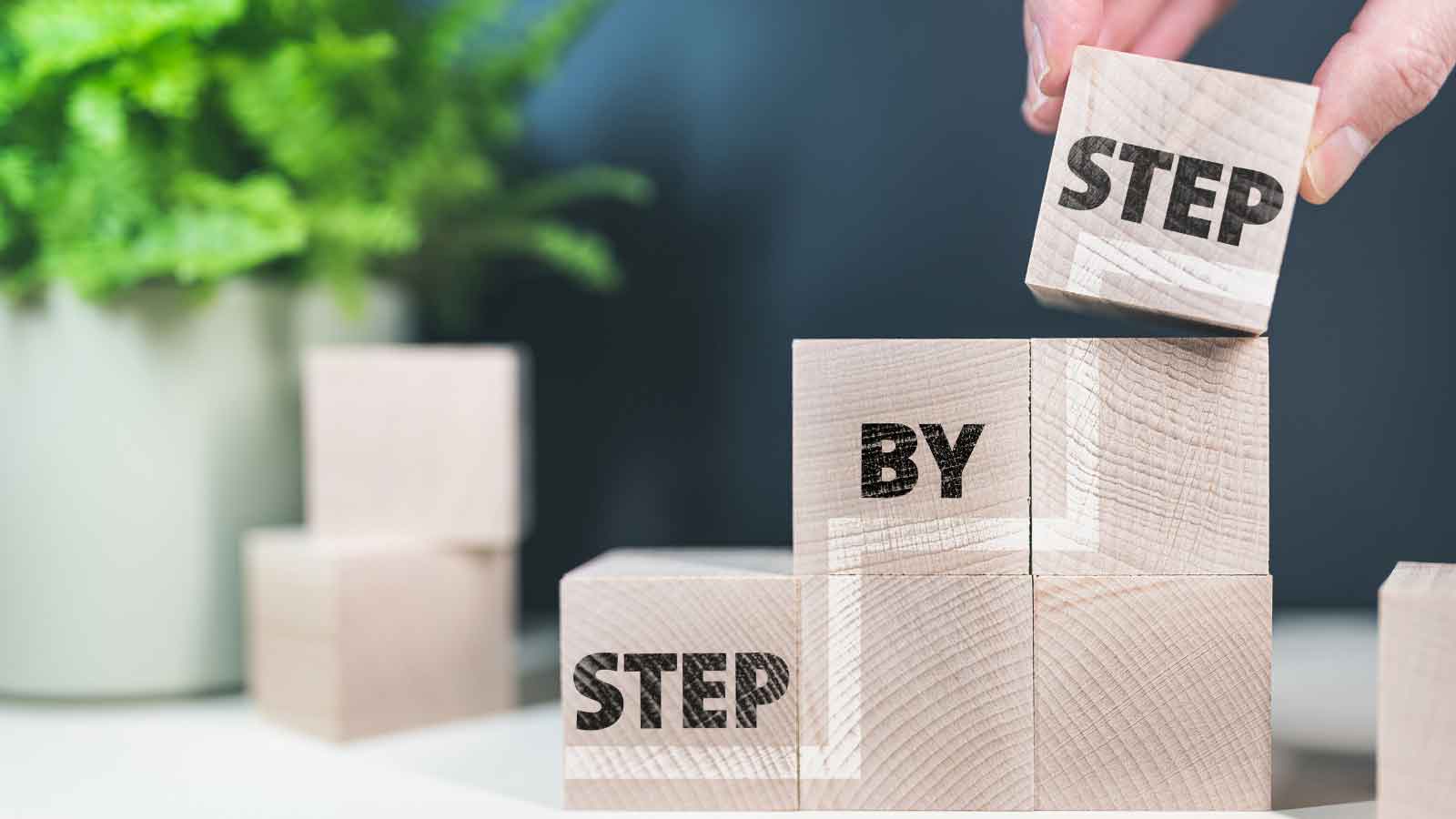Wooden blocks stacked to spell _Step by Step