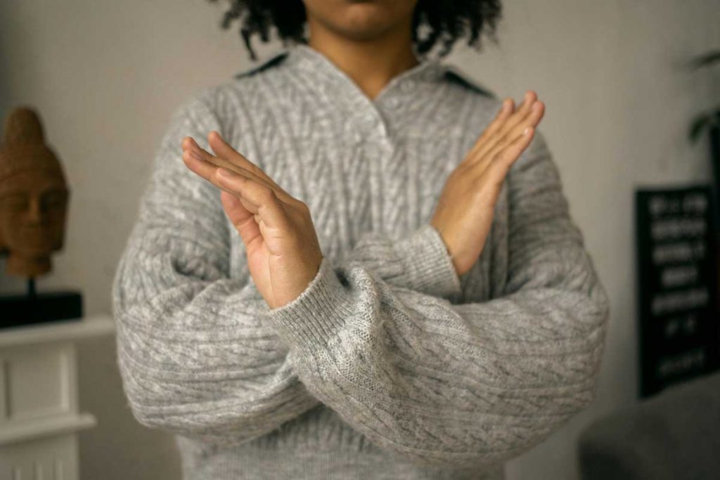 Person setting boundaries with a gesture, symbolizing personal space and self-care. 