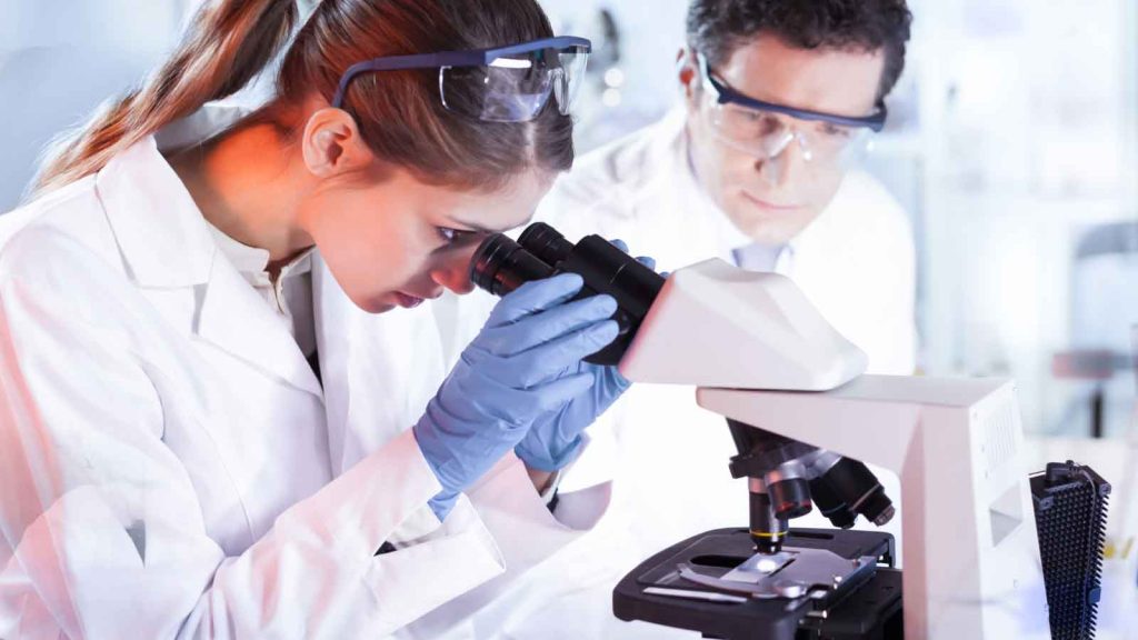 Scientists analyzing samples through a laboratory microscope