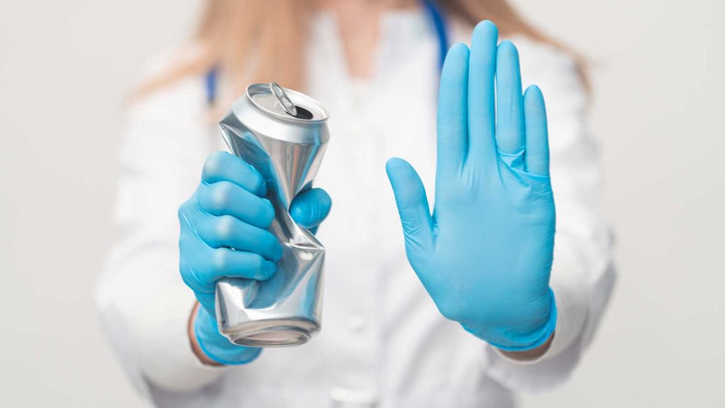 Doctor in gloves holding a crushed can and signaling stop.