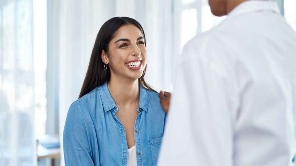 Smiling woman talking to a doctor in a clinic