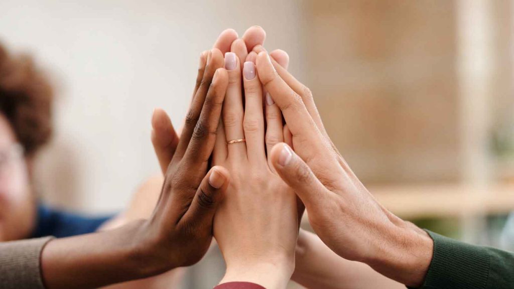 A group of diverse hands joining together in a high-five.