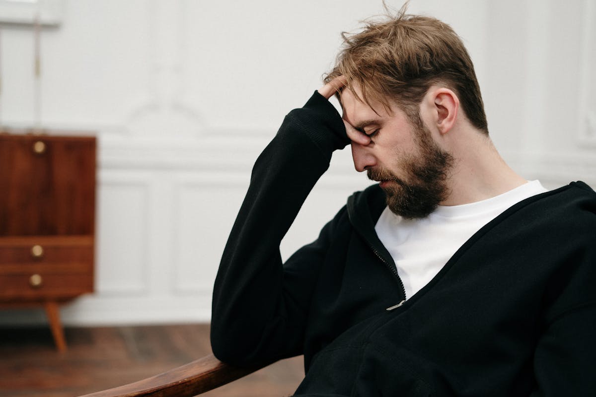 A person sitting with hand on forehead, showing emotional distress during the opioid epidemic