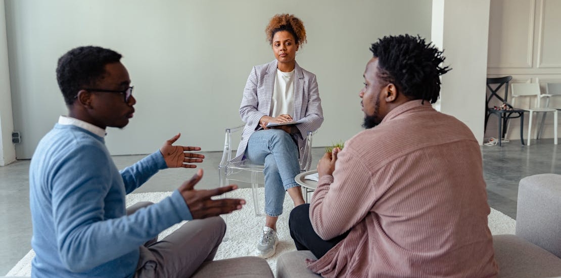 a teen and a dad talking with a therapist about the early signs of bipolar disorder in young adults