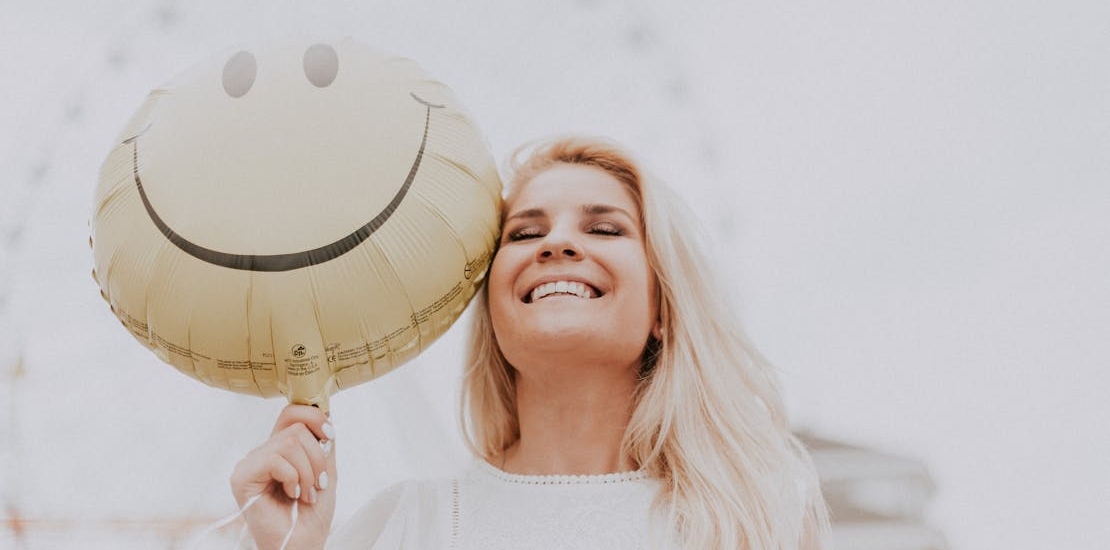 a happy woman holding a yellow ballon