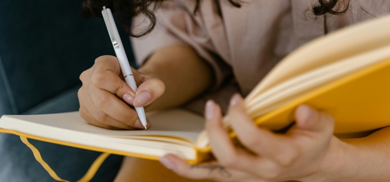 Person writing in a journal about their worries related to social drinking or problem drinking.